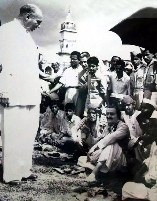 1954 : Darshan programme in Ahmednagar - lunch break. Sarosh Irani ( standing ) talking to Meher Baba. Image courtesy of Lord Meher.
