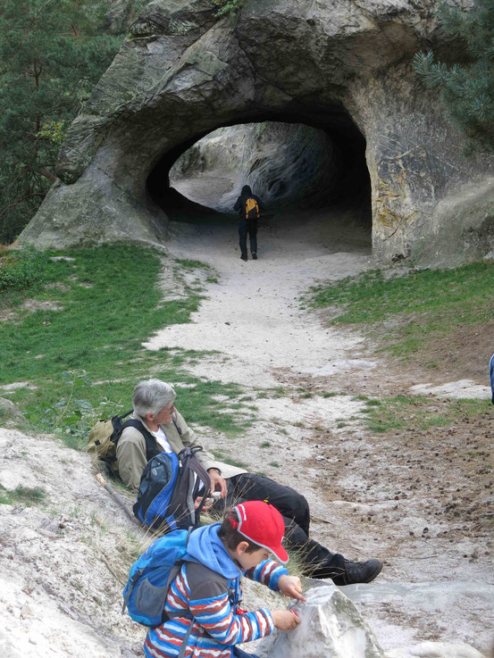 Ein Mann und ein Kind machen Pause vor einer Sandstein-Höhle am Hamburger Wappen bei Timmenrode/ Harz