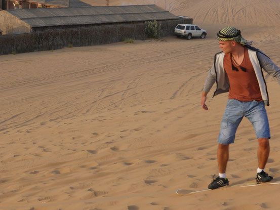 Ich fahre mit dem Board eine Sanddüne hinab.