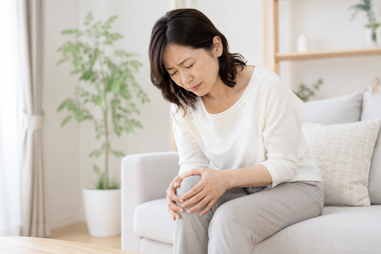 膝が痛くて膝に手をそえる女性