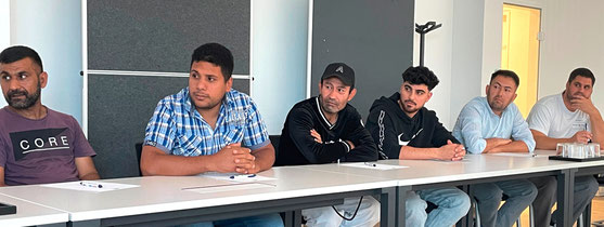 Einige Zuhörer sitzen an Tischen und verfolgen Vortrag