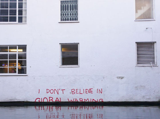 photo of a white buidling with the red words spray-apinting onto it