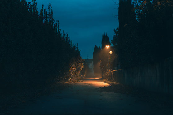 Eine wenig beleuchtete Straße in der Dämmerung. Foto von Andrea Bova auf Pexels.