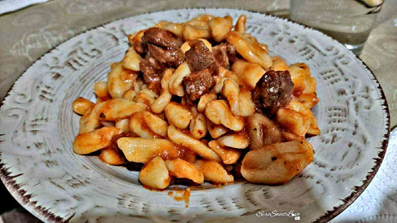 Maccarrones de poddighe pronti e conditi con sugo di carne di cinghiale e formaggio grattugiato di pecora