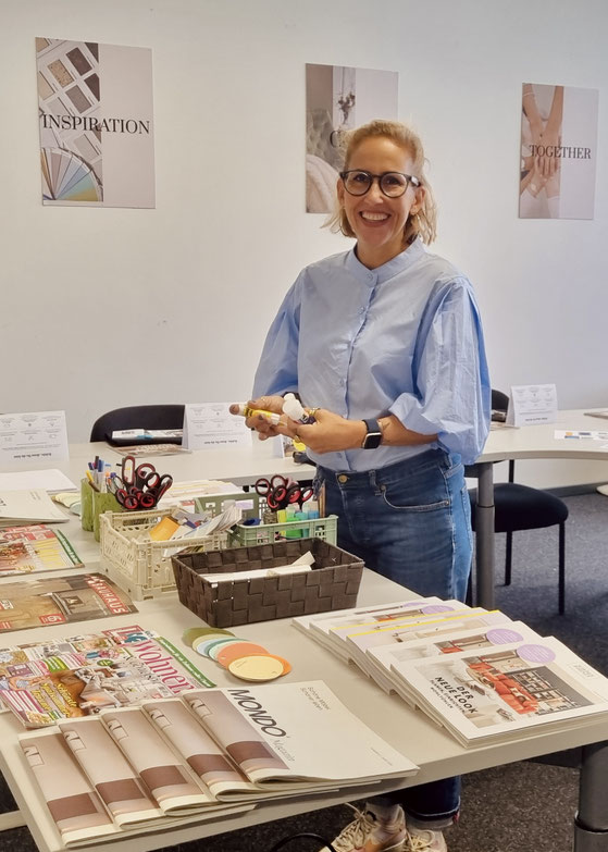 Nora Böhm im hellblauen Hemd mit Puffärmeln mit Stiften und Workshop Materialien zum basteln von Moodboards