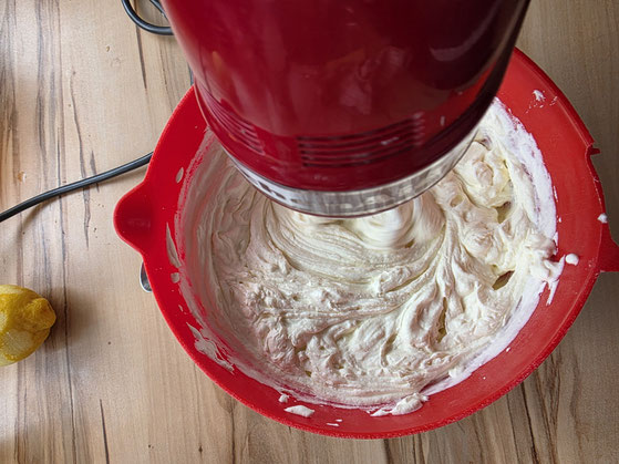 Geschlagene Sahne mit dem Handmixer unter die Quarkcreme rühren