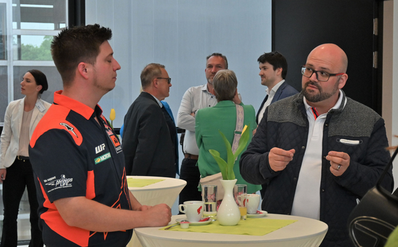 Zwei Teilnehmer an Stehtisch in regem Gespräch.