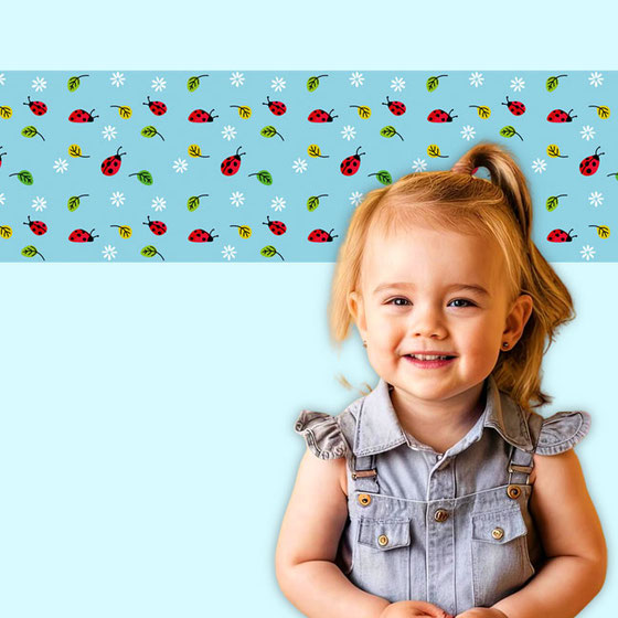 hübsche Kindervliesbordüre mit kleinen roten Marienkäfern, grünen Blättern und weißen Gänseblümchen auf hellblauem Hintergrund