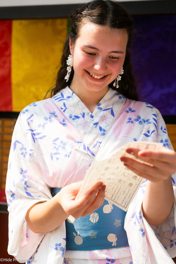 Woman in kimono reading an omikuji fortune at a Japanese shrine in Tokyo
