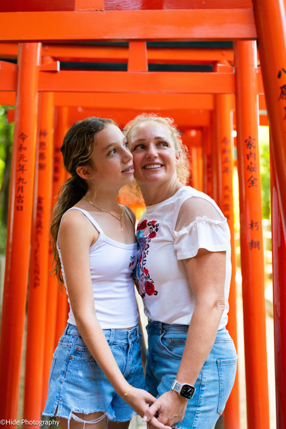 Mother and daughter walking through the iconic red torii gates at Nezu Shrine in Tokyo