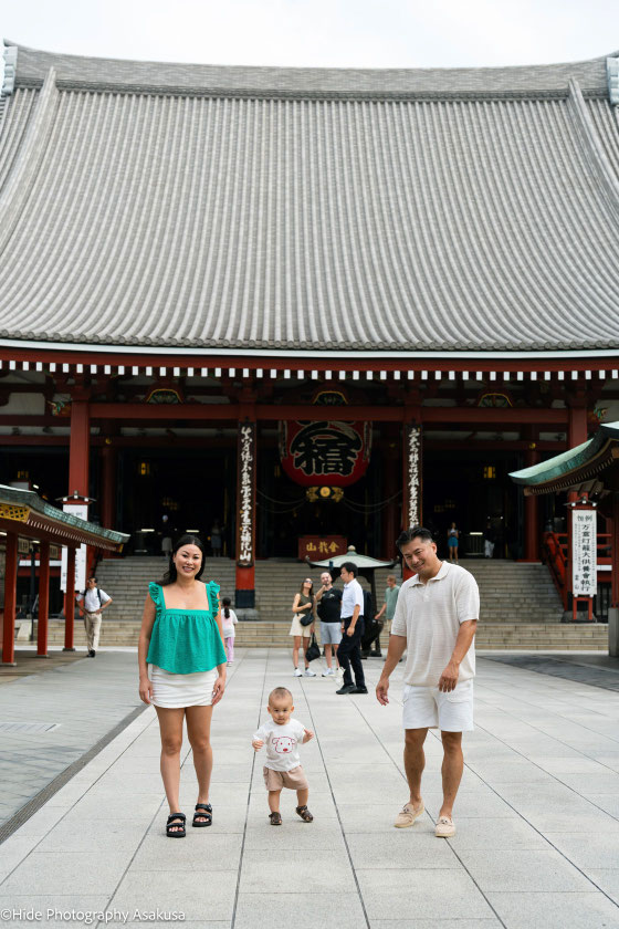 Baby taking first steps between parents at Sensoji Temple during a family photoshoot in Asakusa Tokyo