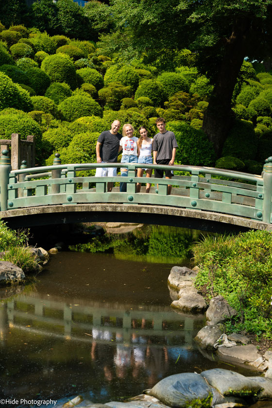 Family portrait on a bridge surrounded by lush gardens during a peaceful morning photoshoot in Tokyo