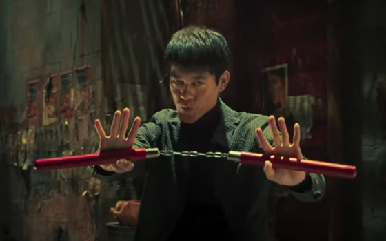 Kwok-Kwan Chan spielt die Rolle des Bruce Lee und hält das Nun-Chaku in die Kamera.
