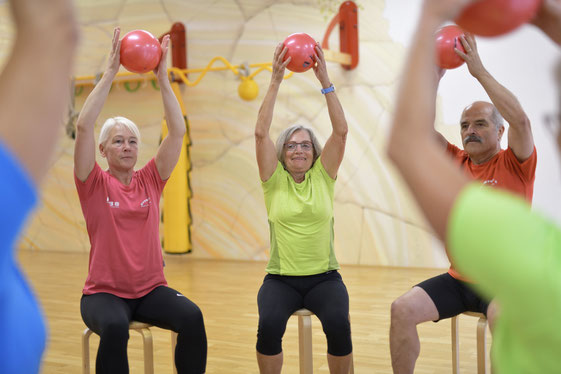 Foto: Sportgruppe bei einer Übung im Sitzen mit einem Gymnastikball