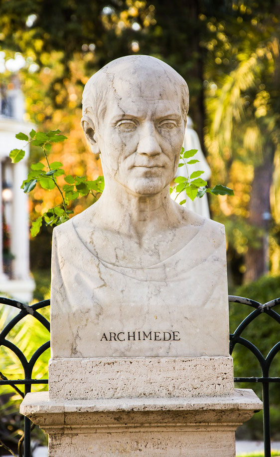 A marble bust of Archimedes, set outdoors with foliage and soft sunlight in the background, showcasing a serene expression and classical design on a stone pedestal.