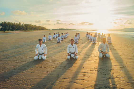 Karateka im Seiza am Strand bei Sonnenaufgang.