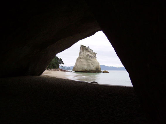 Blick durch die Höhle auf eine spektakulären Felsen am Strand