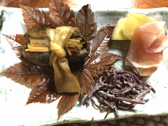 アケビの皮を干しておき、中に根菜類や一粒ずつ自分で潰した打ち豆を入れてかんぴょうで結び、煮る。さつまいもも自家製。右下は赤こごみ