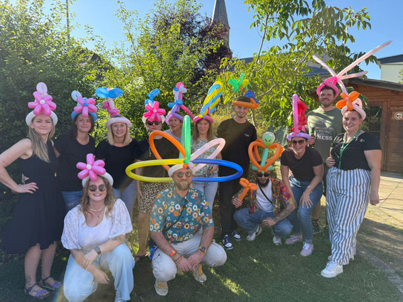 Erwachsene mit bunten Ballonhüten genießen Ballonkunst auf einer Feier – Ballonkünstler für Hochzeiten, Firmenfeiern und Events im Rhein-Main-Gebiet.