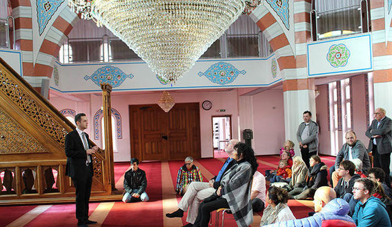 Halil Sahin (links), Generalsekretär der Fatih Moschee in Pforzheim, erklärt den Besuchern bei der Führung durch das islamische Gotteshaus am bundesweiten "Tag der offenen Moschee" den Gebetsraum.