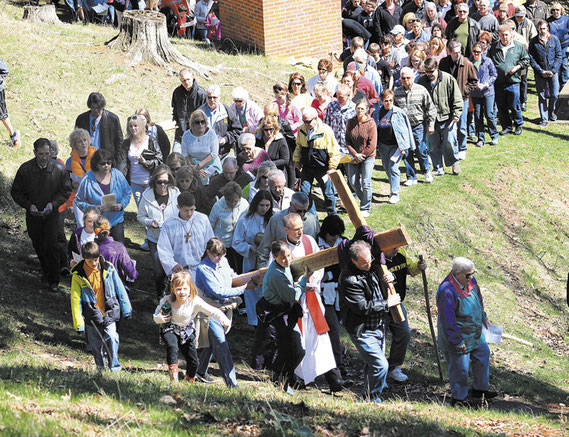 Hundreds attended the Outdoor Way of the Cross service in St. Donatus on Good Friday. Above, the cross is carried past the stations to the old Chapel on the bluff overlooking the church and the community.