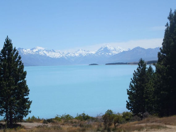 Blick über den azurblauen Lake Pukaki auf die verschneiten Southern Alpes, der größte Berg ist Mt. Cook