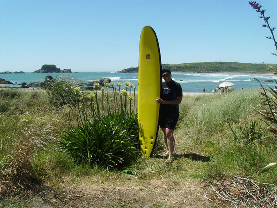 Mein gelbes Surfboard und ich am Strand in der Tauranga Bay