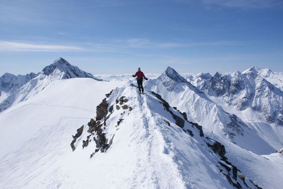 Die letzten Meter geht es zu Fuß über den Gipfelgrat zum höchsten Punkt. Im Hintergrund Roter Knopf, Glödis und Hochschober (von links nach rechts)
