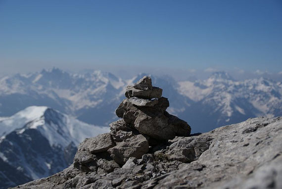 Einzelne Steinmännchen weisen den Weg; im Hintergrund die Karnischen Alpen
