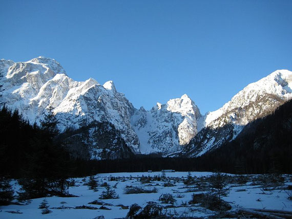 Beim Zustieg über die flache Wiese, links im Bild erhebt sich der Mangart (2677m) und in der Bildmitte die Lahnscharte