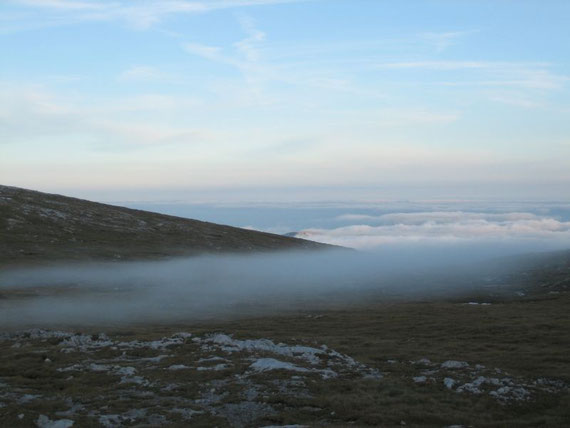 Flache Nebel knapp unterhalb des Gipfels, im Tal liegt Hochnebel