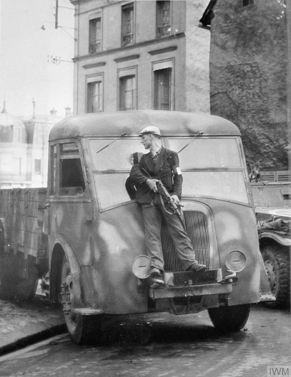 Un membre des Forces françaises de l'intérieur (FFI) avec un Sten SMG utilise un camion pour se couvrir lors de combats au canon avec des tireurs d'élite allemands à Dreux - août 1944