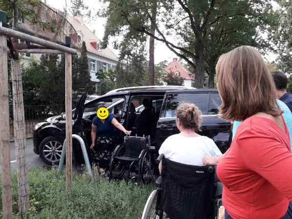 Eine Frau entlädt ihren Rollstuhl mittels eines Verladesystems aus ihrem schwarzen Auto.