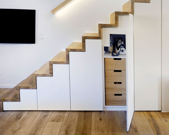 Hinter den Schranktüren bei diesem Einbauschrank unter der Treppe ist viel Stauraum.