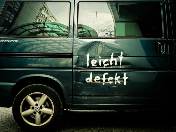 Seitenausschnitt eines grünen Autos, dessen Seitentür zerkratzt und eingebeult ist. Darauf gesprayt mit weißer Farbe der Spruch "leicht defekt" / Bild: pixabay