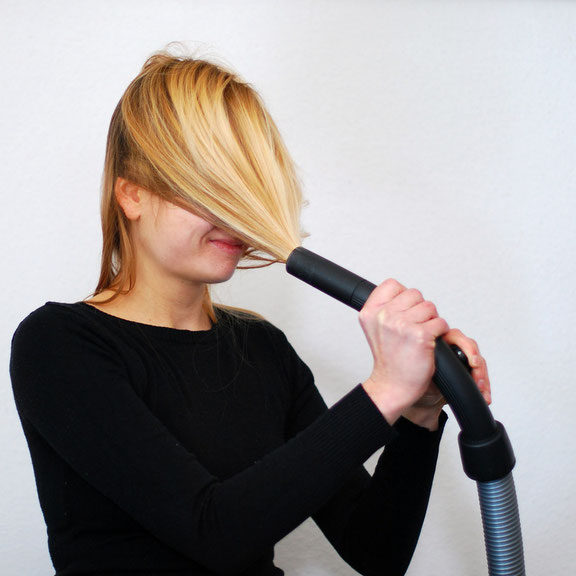 Frau mit Haaren im Staubsaugerrüssel