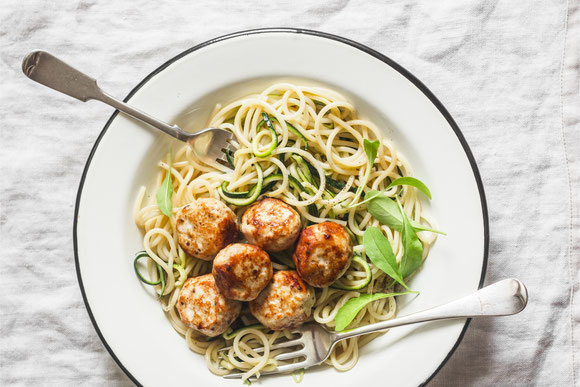 Spaghetti mit Zucchini und Meatballs auf weißem Teller Top View