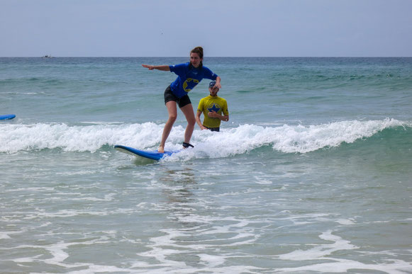Surferin-reitet-Welle-im-Hintergrund-der-Surf-Lehrer