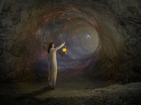 Un homme marche dans une grotte comme un tunnel, une lumière à la main.