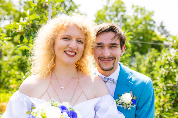 Inniges Hochzeitspaar steht Stirn an Stirn im Park. 