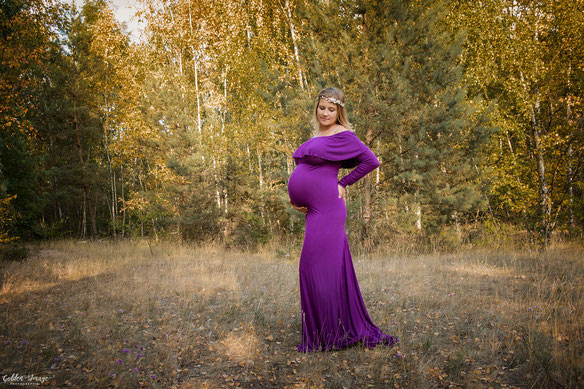 Schwangere Frau im Babybauchkleid in der Natur bei Sonnenschein