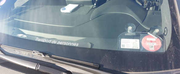 image montrant un parebrise de voiture avec le maracon de VTC véhicule de transport avec chauffeur, ainsi que la carte professionnelle de VTC conformément à la règlementation en vigueur en France