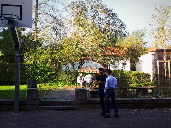 Jugendliche stehen und sitzen im Hinterhof