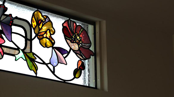 ルヴェール制作の二連ステンドグラスパネル。赤・青・黄色の花々が横長窓を彩る住宅用装飾作品。