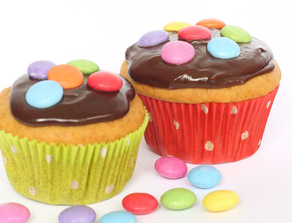 Muffins dekoriert mit Schokoladenguss und bunten Smarties