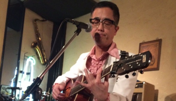 チャーリー坂本が横浜市にあるSam's Barで弾き語り演奏している場面