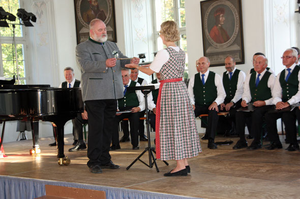 Alexander C. Maschat überreicht bei diesem Anlass den Dirigentenstab des Liederkranzes Tegernsee symbolisch seiner Nachfolgerin Angela Schütz.