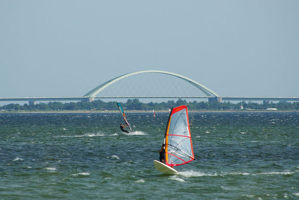 Surfer mit der Fehmarnsundbrücke im Hintergrund