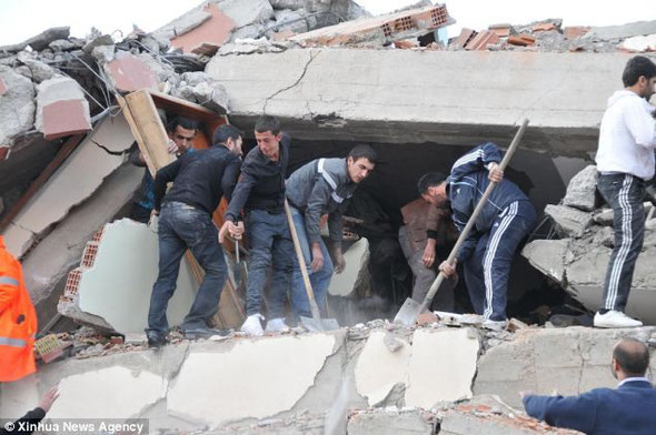 Dangerous work: Local residents risk their lives by digging into crushed floors in Turkey's south-eastern province of Van. They defied collapsing buildings and aftershocks today in a bid to reach trapped victims