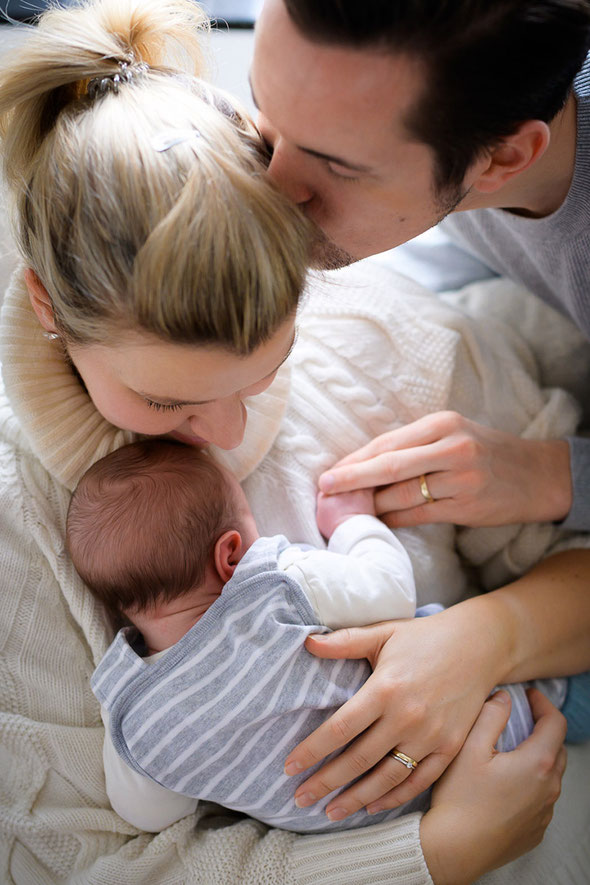 Glückliche Eltern umarmen ihr neugeborenes Baby.
